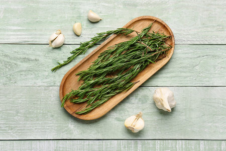 Board with fresh rosemary and garlic on color wooden backgroundの写真素材