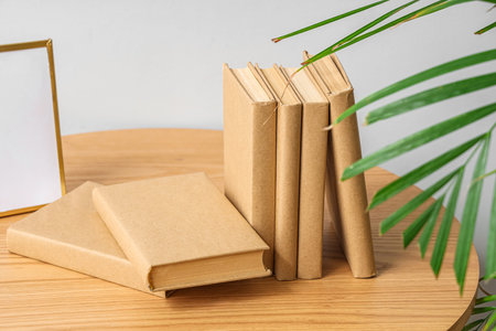 Books on wooden table near light wall, closeup
