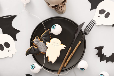 Halloween table setting with skull and tasty cookies on light background, closeupの写真素材