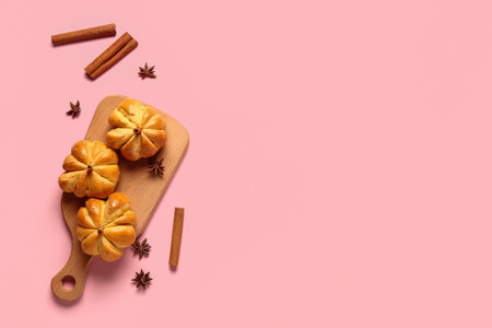 Wooden board with tasty pumpkin shaped buns on pink backgroundの写真素材