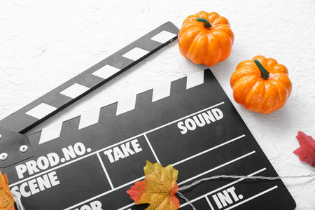 Clapperboard with Halloween decor on textured white backgroundの写真素材