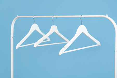 Rack with wooden clothes hangers on blue backgroundの写真素材
