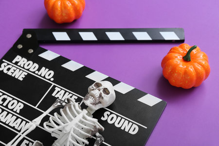 Clapperboard with pumpkins and skeleton on purple background. halloween celebrationの写真素材