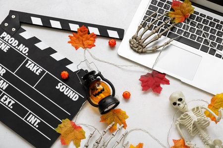 Clapperboard with laptop and different Halloween decor on white backgroundの写真素材