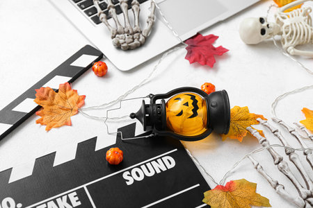 Clapperboard with laptop and different Halloween decor on white backgroundの写真素材