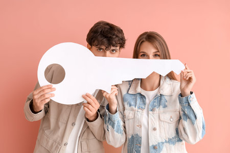 Young couple with paper key on color background