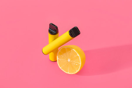 Electronic cigarettes with lemon on pink background