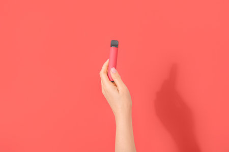 Woman holding electronic cigarette on red backgroundの写真素材