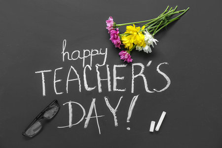 Beautiful flowers with eyeglasses and text HAPPY TEACHER'S DAY on black chalkboardの写真素材