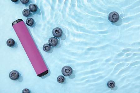 Electronic cigarette with blueberry in water on blue backgroundの写真素材