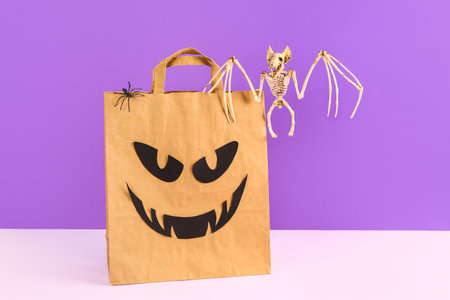 Shopping bag with spider and bat skeleton for Halloween on lilac backgroundの写真素材