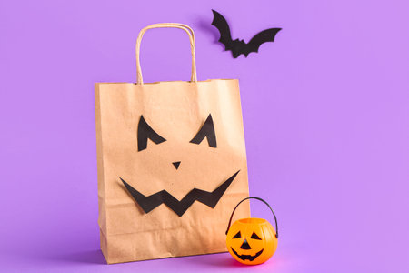 Shopping bag, basket in shape of pumpkin and bat for Halloween on lilac backgroundの写真素材