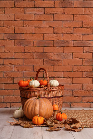Wicker basket with pumpkins and leaves near brick wall. Halloween celebrationの写真素材
