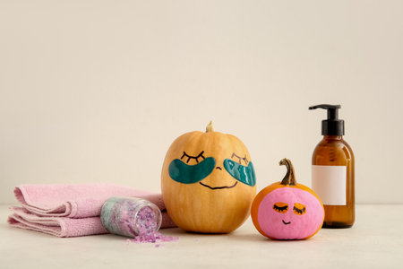Pumpkins with under-eye patches, mask and spa supplies on light backgroundの写真素材