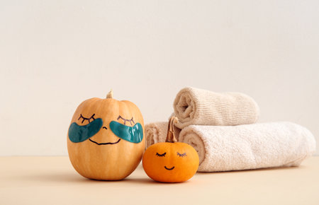 Pumpkins with under-eye patches and towels on beige backgroundの写真素材