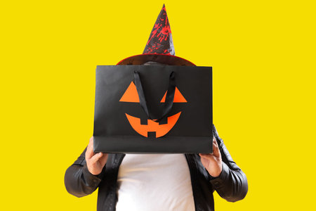 Mature man with Halloween gift bag on yellow backgroundの写真素材