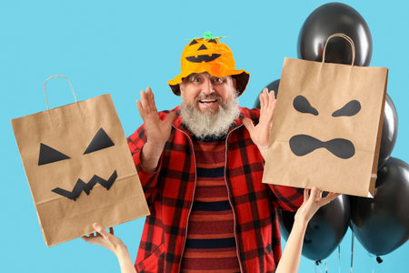 Mature man dressed for Halloween with gift bags and balloons on blue backgroundの写真素材