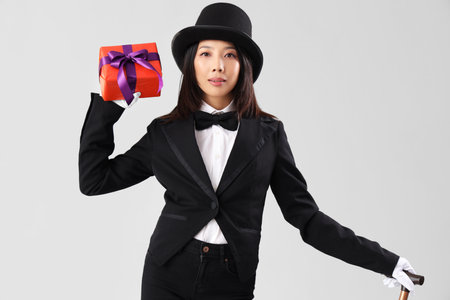 Young Asian woman dressed as magician with Halloween gift on light backgroundの写真素材