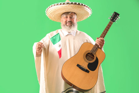 Mature man in sombrero hat with Mexican flag and guitar on green background