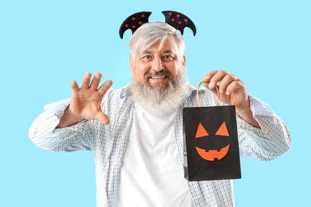 Mature man dressed for Halloween with gift bag on blue backgroundの写真素材