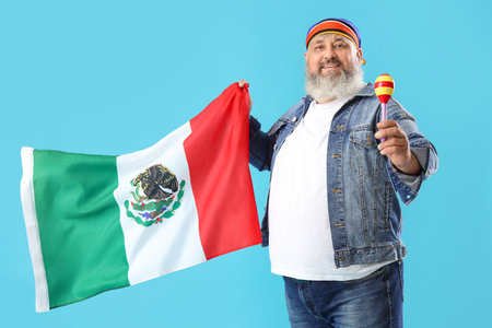 Mature man with Mexican flag and maraca on blue backgroundの写真素材