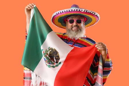 Mature man in sombrero hat with Mexican flag on orange background