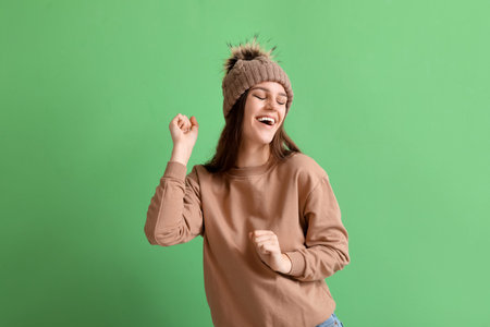 Happy young woman in winter clothes on green backgroundの写真素材