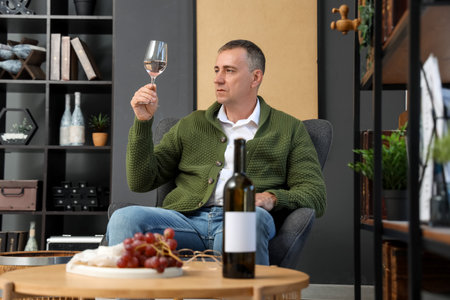 Mature man tasting wine at homeの写真素材