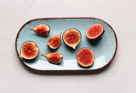 Plate with cut fresh figs on gray background