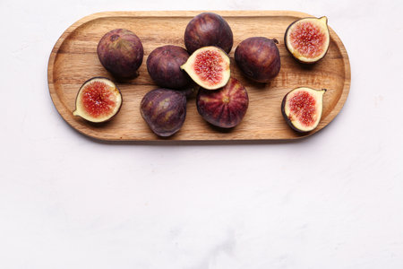 Wooden board with fresh ripe figs on white backgroundの写真素材
