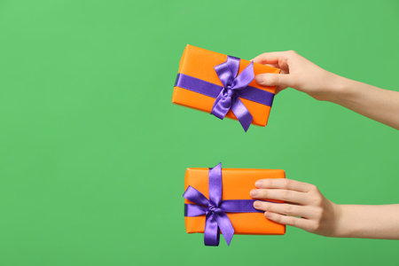 Female hands with Halloween gift boxes on green backgroundの写真素材