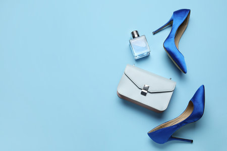 Stylish blue high heels with purse and perfume on color backgroundの写真素材