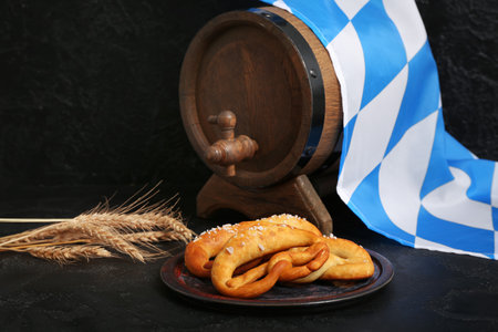 Plate with soft pretzels, barrel of beer and flag of Bavaria on black backgroundの写真素材