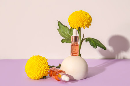 Composition with bottles of essential oil, plaster podium and beautiful chrysanthemum flowers on color backgroundの写真素材