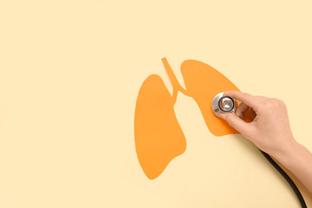 Female hand with stethoscope and paper lungs on beige background. Lung cancer conceptの写真素材