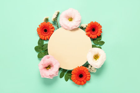 Composition with blank paper sheet and beautiful flowers on turquoise backgroundの写真素材