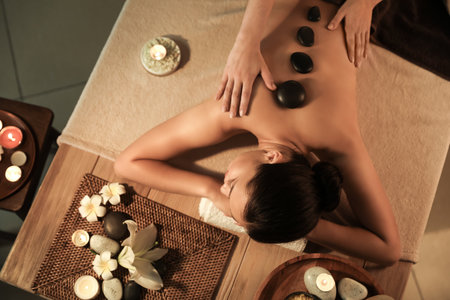 Young woman undergoing treatment with stones in dark spa salon, top viewの写真素材