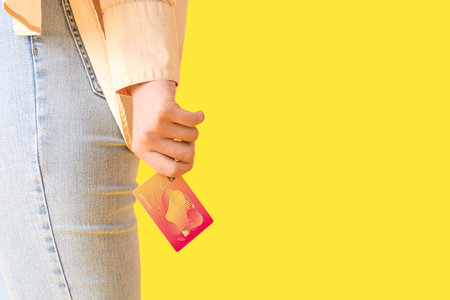 Young woman with credit card on yellow background, closeupの写真素材