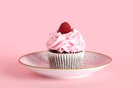 Plate with tasty raspberry cupcake on pink backgroundの写真素材
