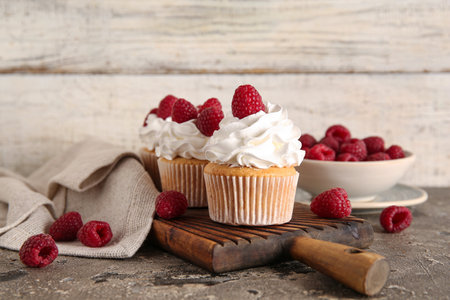Wooden board of tasty raspberry cupcakes and fresh berries on tableの写真素材