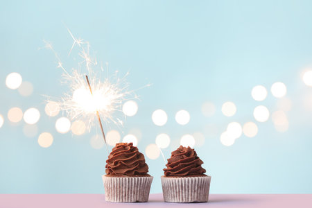 Tasty birthday cupcakes with sparkler on color backgroundの写真素材