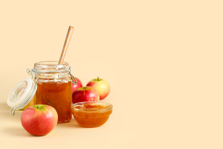 Jar and glass bowl of sweet apple jam on orange backgroundの写真素材