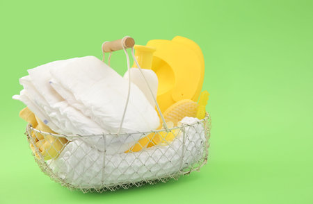 Basket with gifts for baby on green background