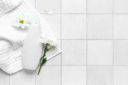 Composition with bottle of cosmetic product, towel and chamomile flowers on light tile backgroundの写真素材