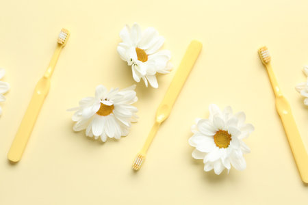 Composition with toothbrushes and beautiful chamomile flowers on color backgroundの写真素材