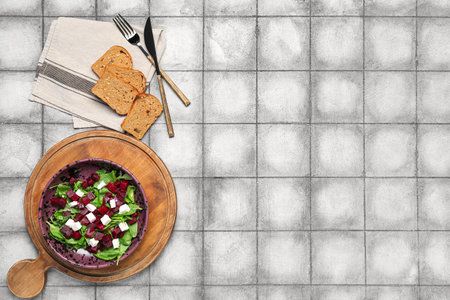 Bowl of fresh vegetable salad with beet and bread on gray tile backgroundの写真素材