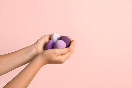 Female hands with different makeup sponges on pink backgroundの写真素材