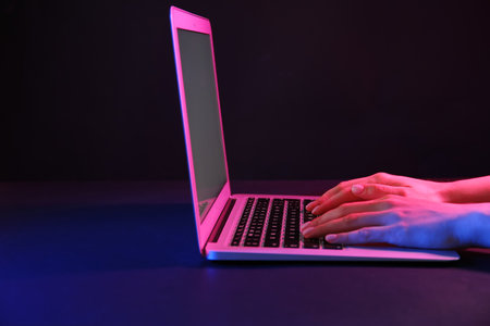 Woman working with modern laptop on black backgroundの写真素材
