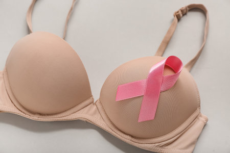 Bra with pink ribbon on gray background, closeup. Breast cancer awareness conceptの写真素材