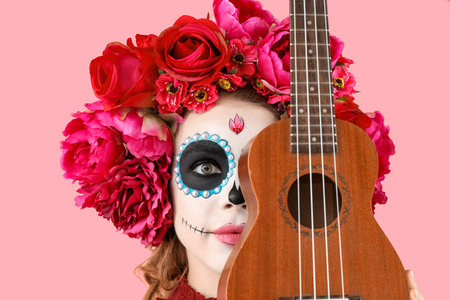 Young woman with painted skull and guitar on pink background, closeup. Mexico's Day of the Dead (El...